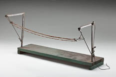 This model of a multiple-strand rope start barrier was made in the 1940s by Reuben Gray. Reuben’s father, Alexander, developed a pioneering single-strand start barrier. He was inspired to create the technology after Reuben, who worked as a jockey in his youth, received a fine for a false start. Reuben went on to develop the stronger multiple-strand start barrier.