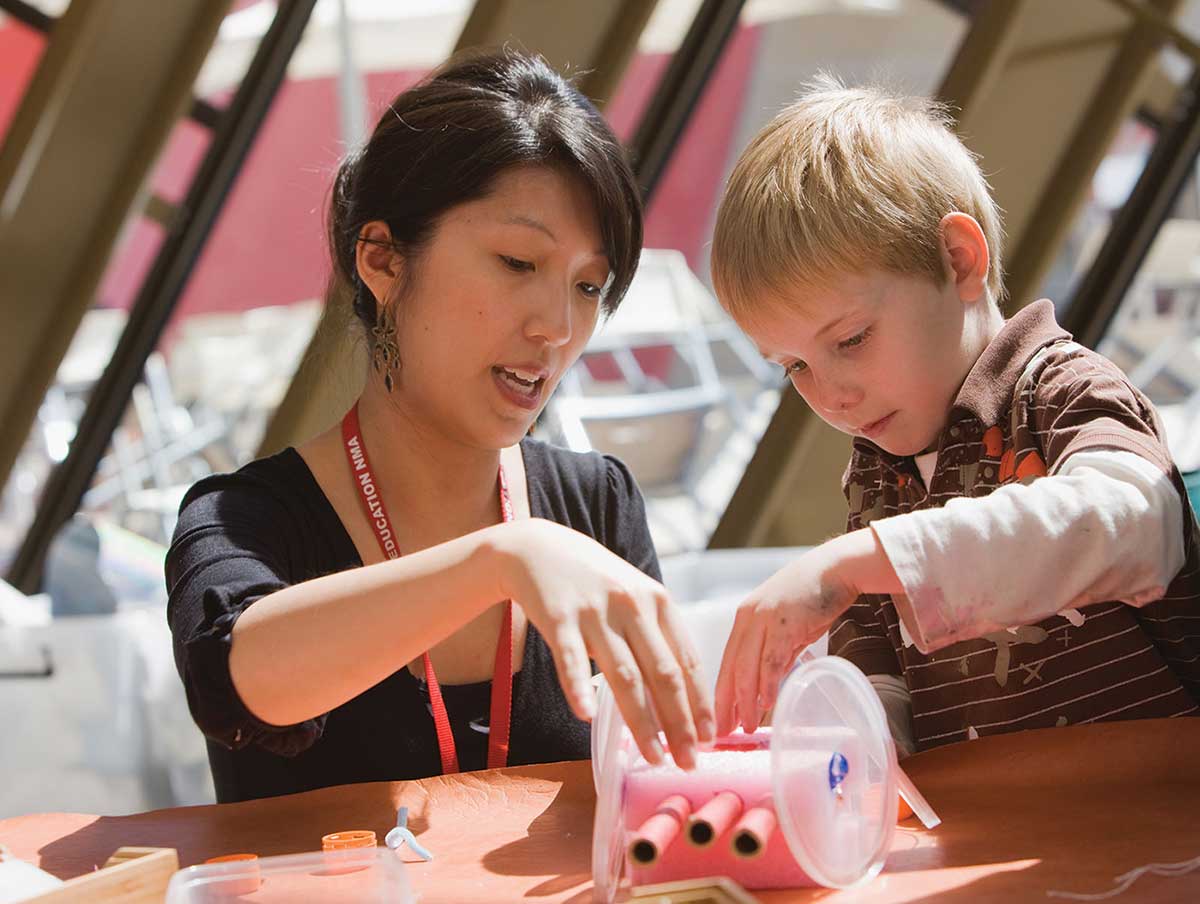 A volunteer assists a young Museum visitor at Discovery Space in the Hall.