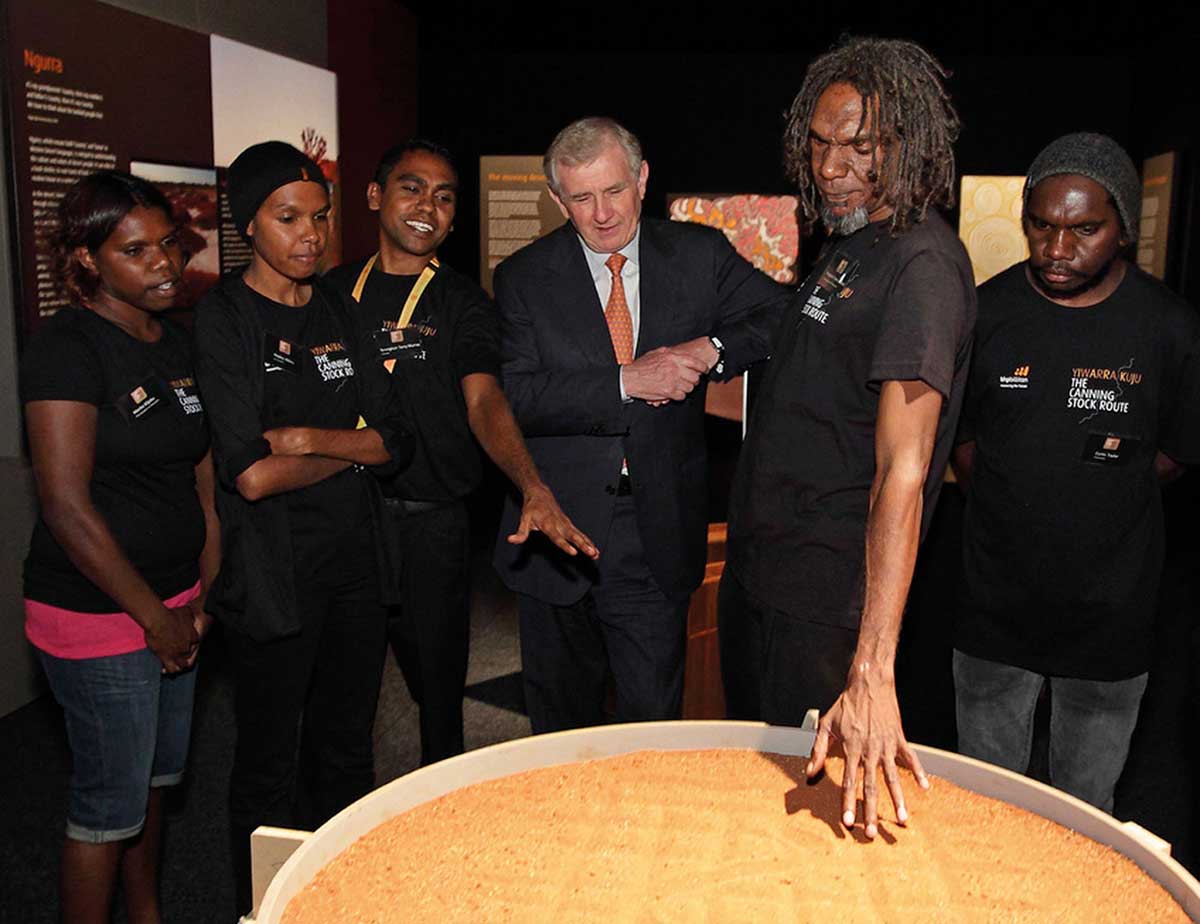 A group of people surrounding an object containing sand.