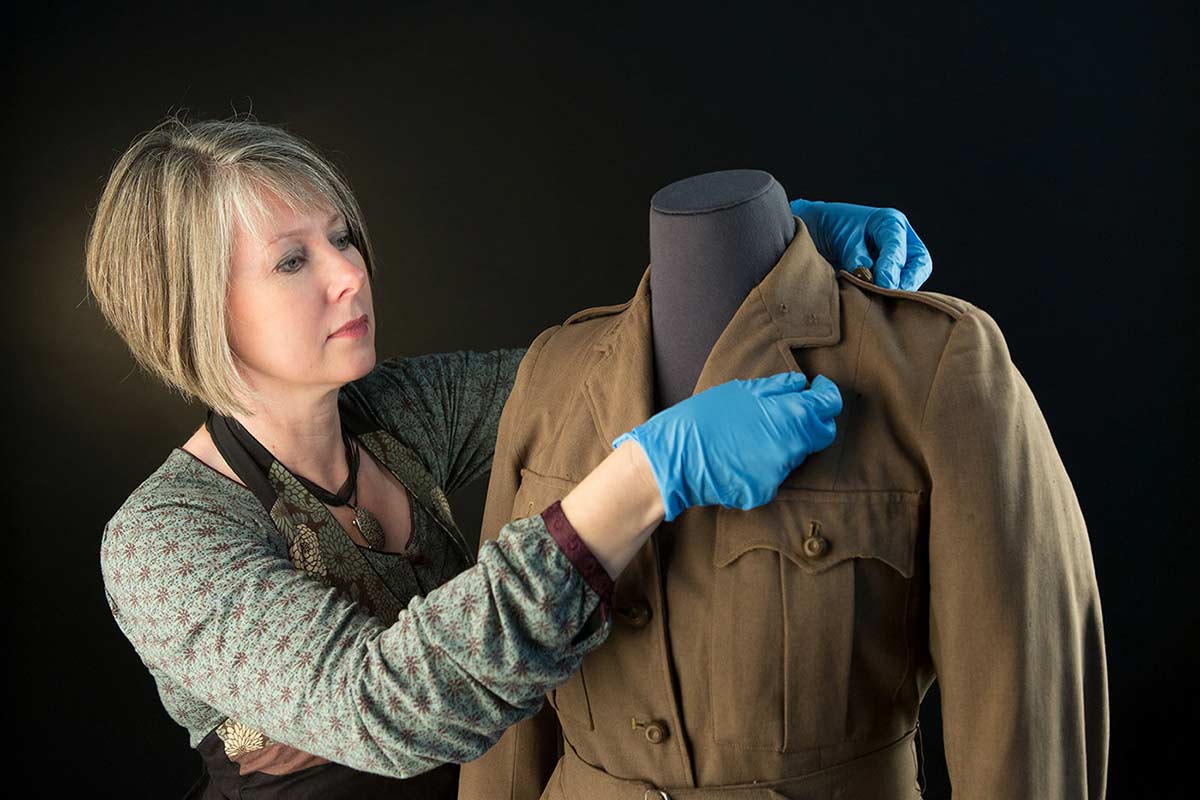 Conservator Michelle Newton-Edwards working on a woollen jacket worn by a member of the Australian Women’s Army Service.