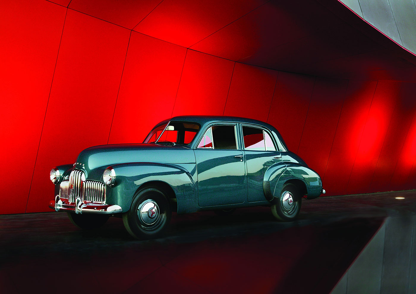 Holden model car on display in front of a red wall.