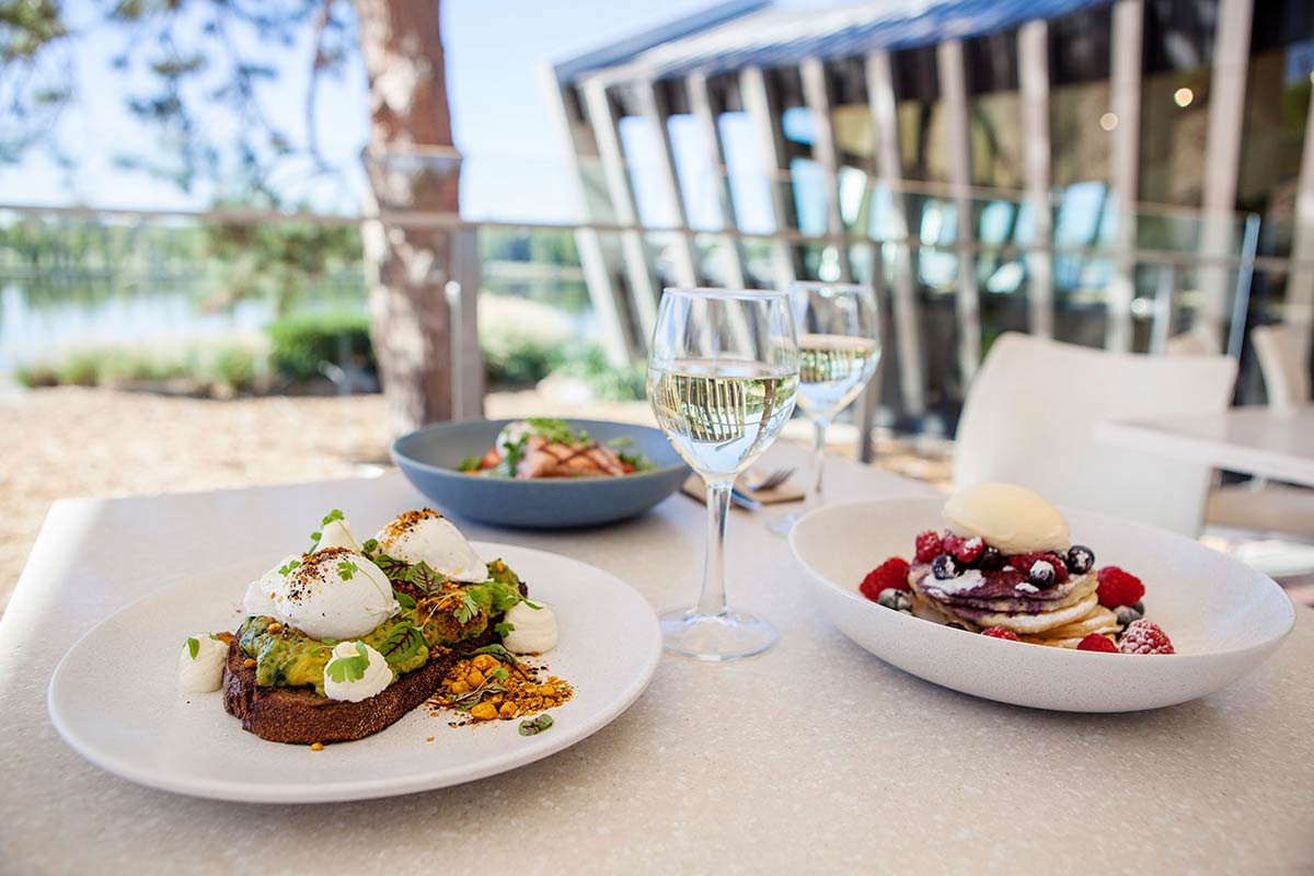 Two plates of food and two glasses of wine.