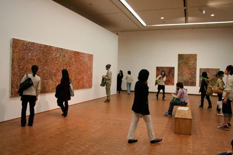 Visitors looking at Emily Kngwarreye paintings in the exhibition.